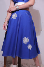 A woman wearing a Blue dress with white floral embroidery