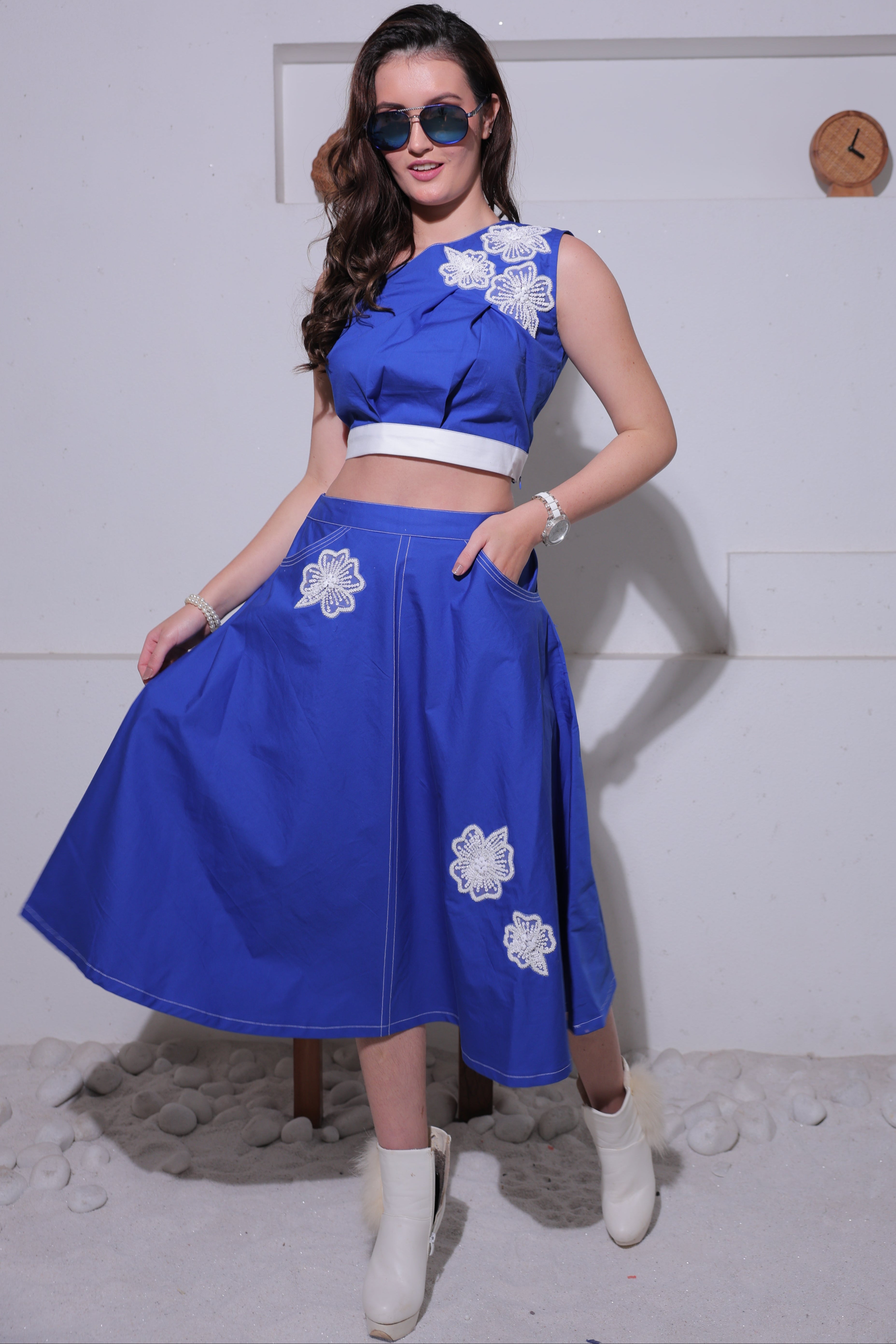 A woman wearing a blue dress with white floral patterns on a white background