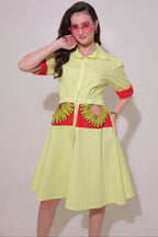 Woman wearing a lime green outfit with red accents and a floral pattern on a plain background