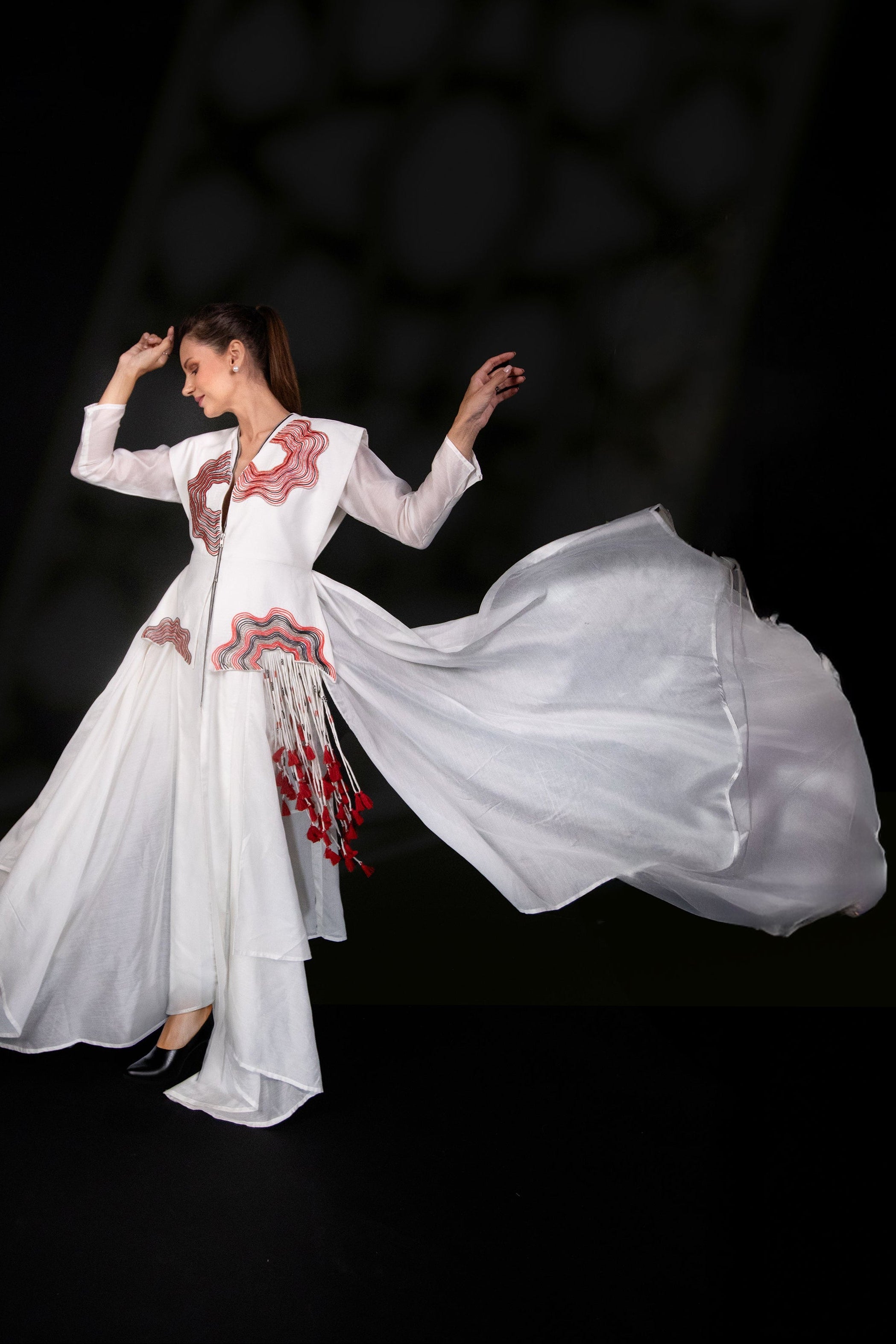 Woman in a white dress with red embroidery on a black background